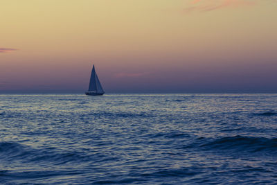 Sailboat sailing on sea against sky during sunset