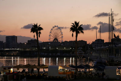 View of ferris wheel in city at sunset