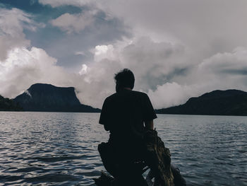 Rear view of man standing by sea against sky