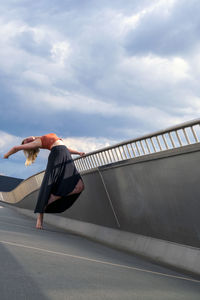Side view of person skateboarding on bridge against sky