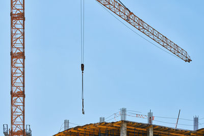 Low angle view of crane against clear blue sky