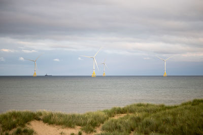 Wind turbines on field against sky