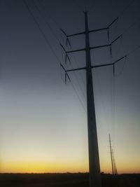 Electricity pylons on landscape at sunset