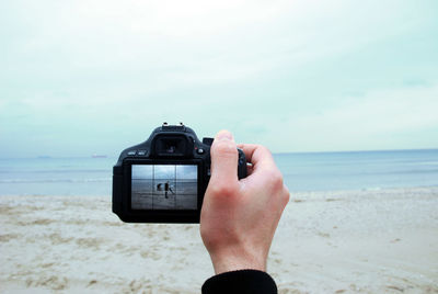 Close-up of person photographing sea against sky