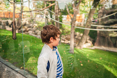 Boy looking away while standing at park