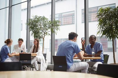 Multi-ethnic medical team sitting at cafeteria in hospital