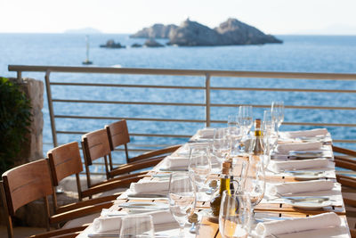 Chairs and tables at dining table by sea against sky