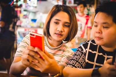 Close-up of friends using mobile phone in shop