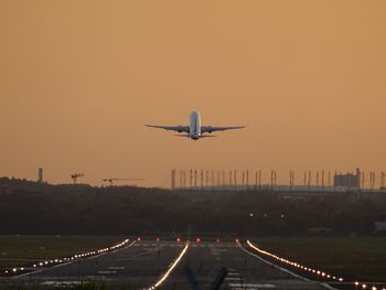 Airplane taking off against sky during sunset