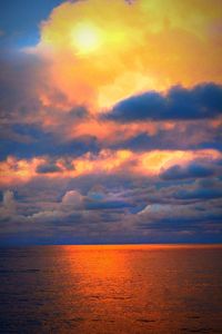 Scenic view of sea against cloudy sky at sunset