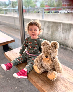 Cute girl waiting with her teddy bear at the bus station