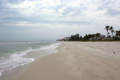 Scenic view of beach against cloudy sky