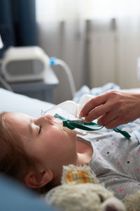 Cropped hand wearing oxygen mask to girl