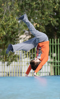 Kid making somersault somersault outdoor in inflatable air cushion jumping bouncer playground.