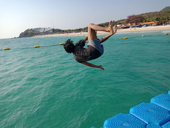 Man jumping in sea against sky