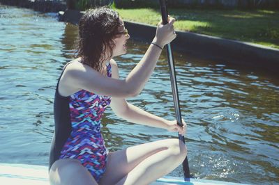 Rear view of woman sitting on boat in river