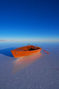 Boat in sea against clear blue sky