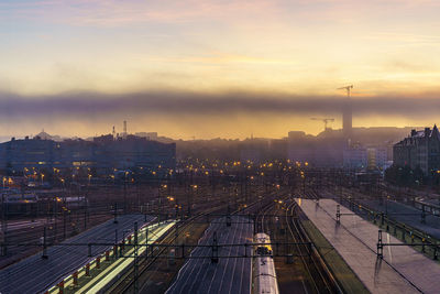 High angle view of railroad tracks by buildings against sky during sunset