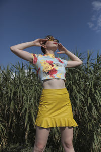 Midsection of woman standing on field against sky