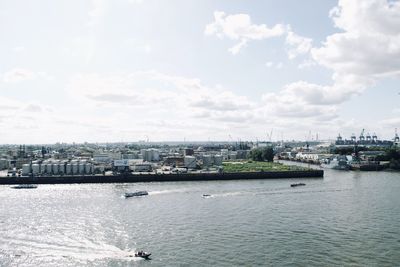 View of cityscape by sea against sky