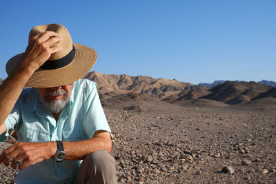 Rear view of woman wearing hat standing at desert against clear sky