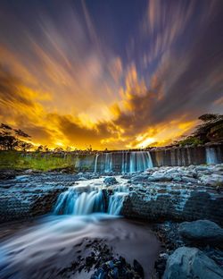 Scenic view of waterfall against sky during sunset