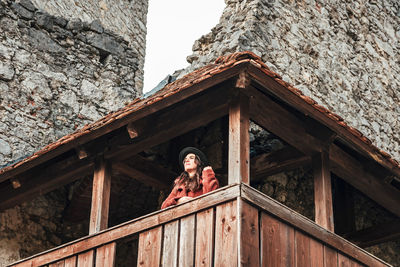 Young woman in winter clothes on wooden balcony of an old medieval castle.