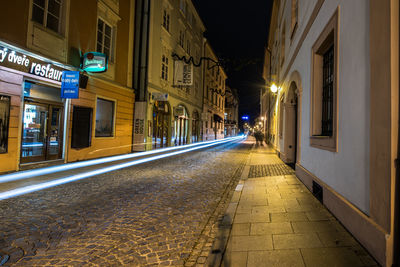 Illuminated street amidst buildings at night