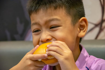 Close-up of boy looking away while eating burger