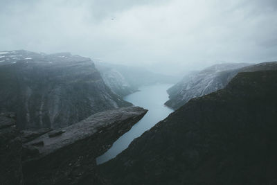 Scenic view of fjord amidst rock formations against sky during winter