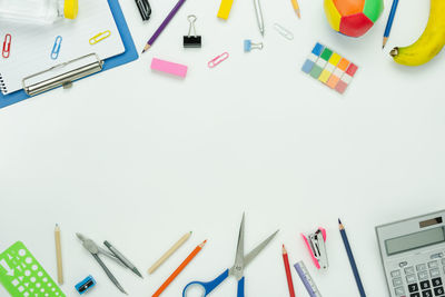 Directly above shot of school supplies with banana and toys over white background