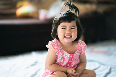 Portrait of cute girl sitting on bed