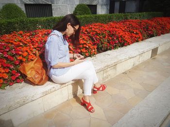 Full length of woman sitting by flowers