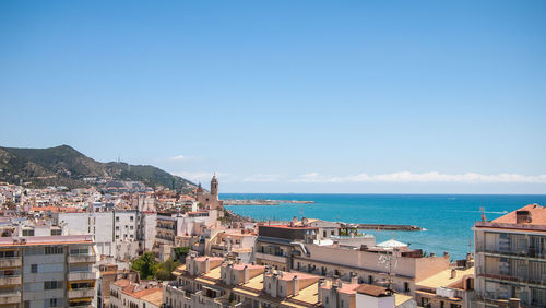 High angle view of townscape by sea against blue sky