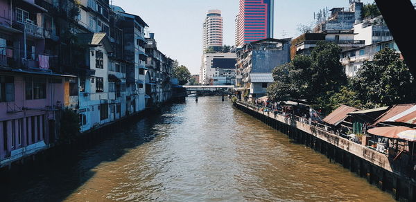 Canal amidst buildings in city against sky
