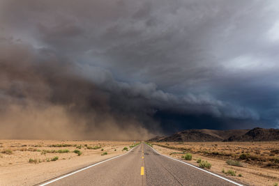 Dark storm clouds and blowing dust approaching a road in the arizona desert.