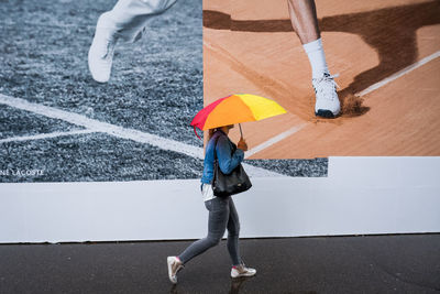 Low section of woman with umbrella standing on street