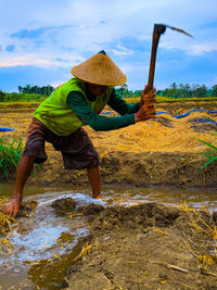 Man holding umbrella on land against sky