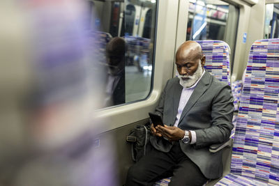 Senior businessman using mobile phone in train