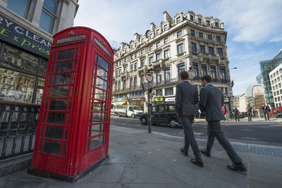 Low angle view of telephone booth against sky in city