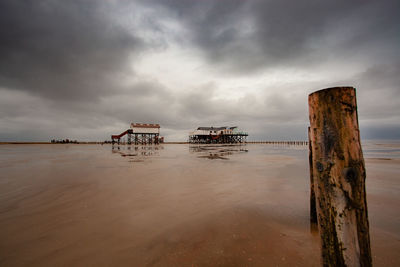 Wooden posts on beach against sky