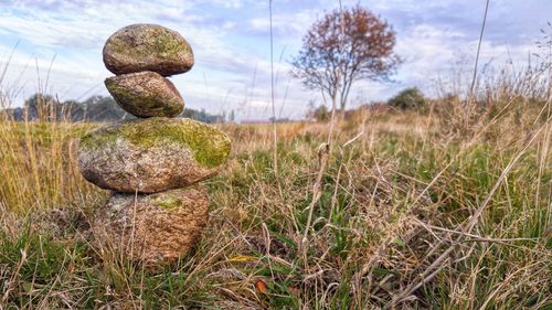 Stack of stones on field against sky