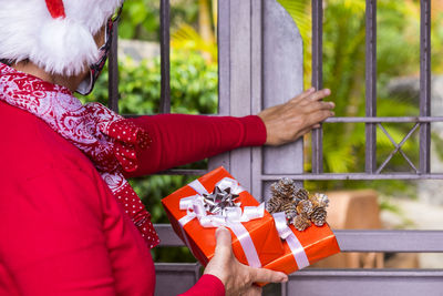 Midsection of senior woman with christmas present standing at gate