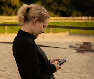 Young blond girl busy on her smartphone