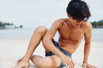 Rear view of shirtless man exercising at beach