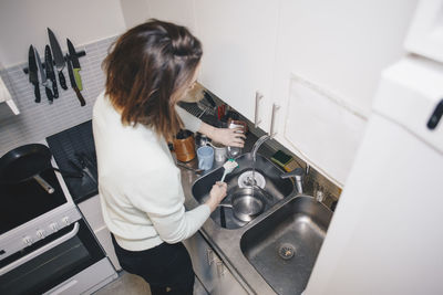 High angle view of woman washing dishes in kitchen sink at dorm
