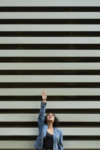 Young woman in abstract background, stretching her hand up.