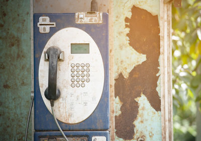 Close-up of old telephone booth on wall