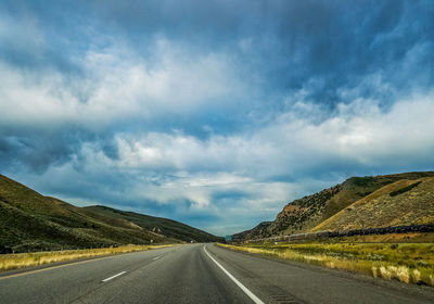 Empty road along landscape against sky