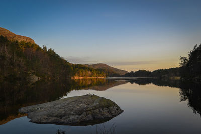 Scenic view of lake by mountains against clear sky